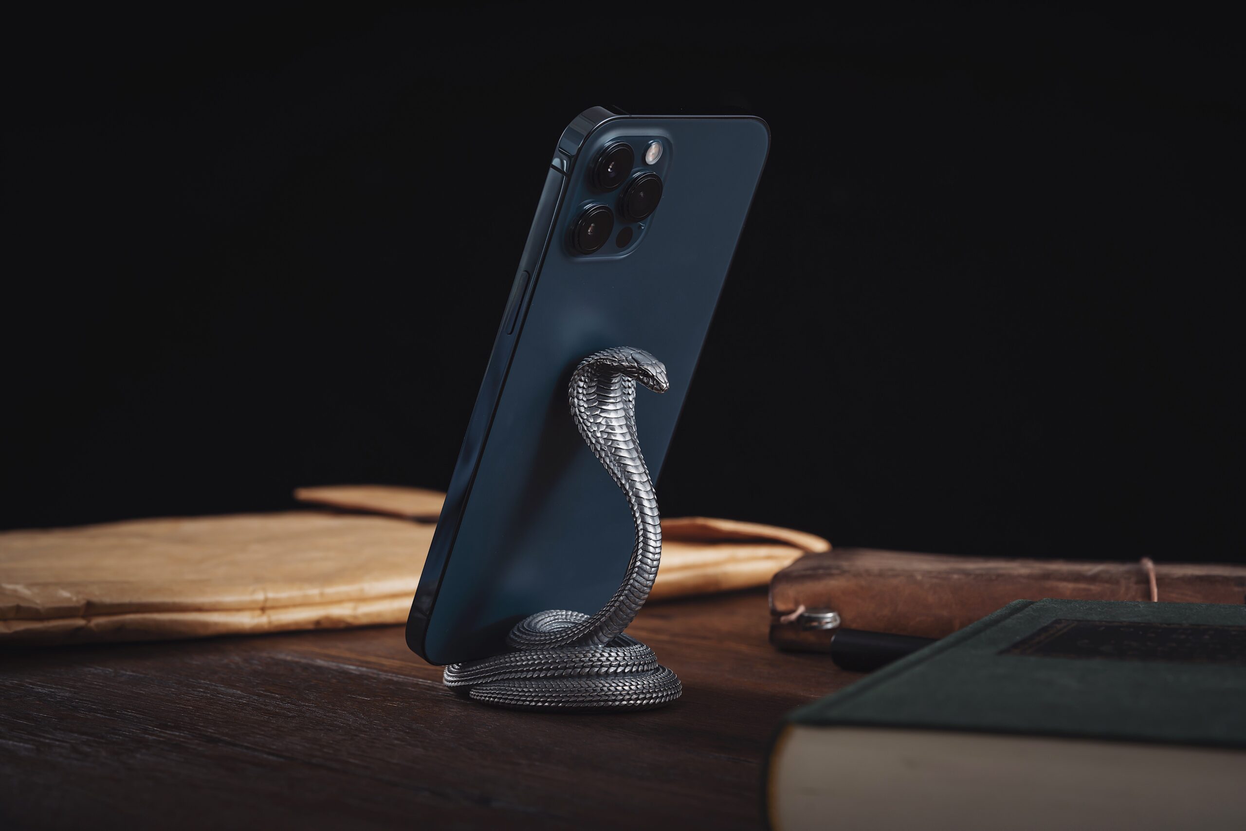 A modern smartphone elegantly displayed on a cobra-shaped stand, adding style to any desk.
