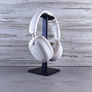 Minimalist photo of white wireless headphones on a stand against wood background.