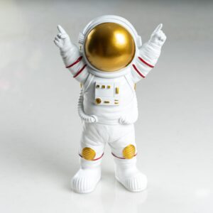 Close-up of an astronaut figurine with a golden visor, raising its hands, on a white background.